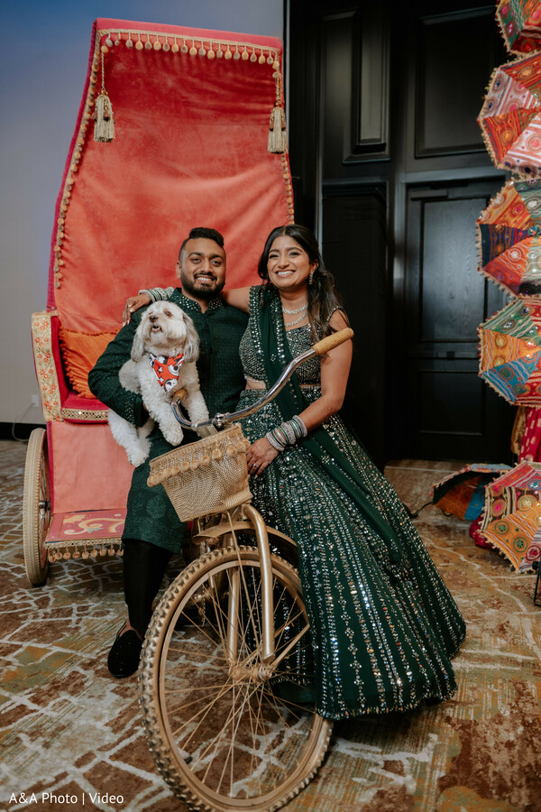couple with dog wedding,rickshaw decor setup,playful wedding portrait,bride green lehenga,groom black sherwani,unique wedding props,pet in wedding shoot,fun couple portrait,cultural decor element,creative wedding photo