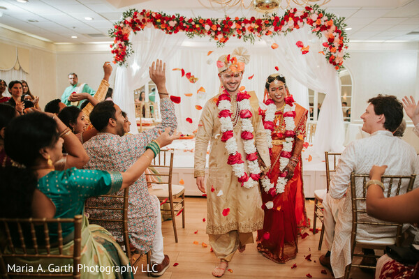 wedding aisle exit,flower petal toss,bride groom garlands,ceremony celebration moment,indian wedding rituals,joyful wedding crowd,newlywed exit,candid ceremony moment,wedding guests cheering,cultural wedding tradition