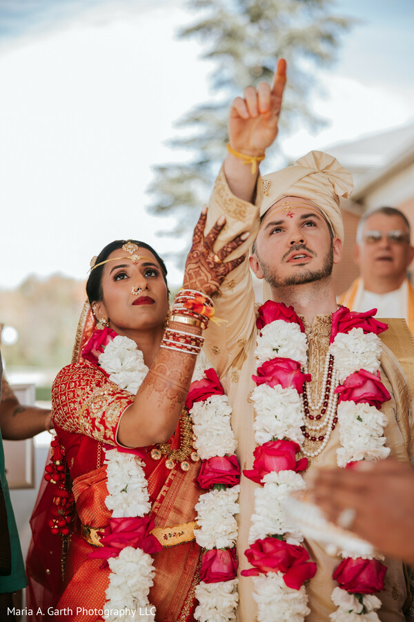 indian wedding ritual moment,bride groom garlands,sacred ceremony action,couple looking up ritual,traditional hindu ceremony,bridal mehndi detail,groom turban sherwani,symbolic wedding ritual,cultural ceremony moment,spiritual wedding scene