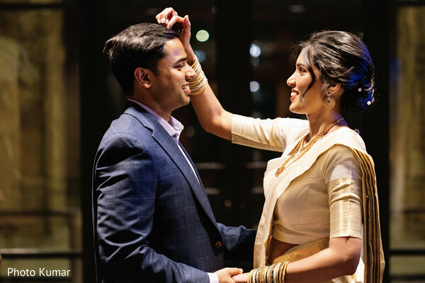 indian pre wedding ritual,bride applying tilak,couple candid moment,traditional ceremony detail,bride gold saree,groom suit portrait,intimate couple interaction,cultural wedding ritual,joyful expression,engagement moment