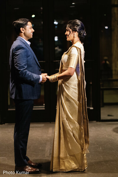 couple holding hands,indian engagement portrait,bride gold saree,groom formal suit,romantic pose standing,elegant couple photo,traditional meets modern,indoor portrait session,love connection moment,pre wedding shoot