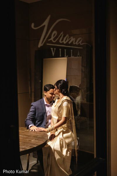 romantic couple candid,indoor evening portrait,intimate couple moment,moody lighting photography,bride gold saree,groom blue suit,reflection shot window,cozy couple setting,engagement session vibe,storytelling photo
