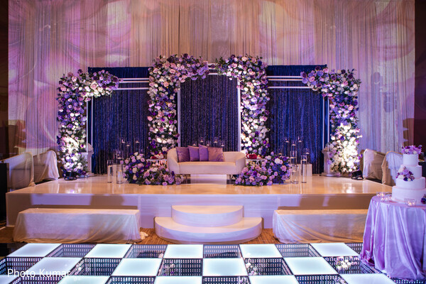 reception stage decor,purple wedding theme,floral backdrop stage,glass dance floor,wedding venue setup,luxury reception design,event styling details,elegant wedding decor,stage centerpiece,ballroom setup