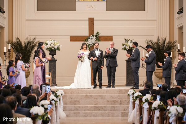 church wedding ceremony,christian wedding moment,bride white gown,groom black tuxedo,altar vows,multicultural wedding,ceremony aisle decor,wedding guests witnessing,traditional church setting,wedding vows