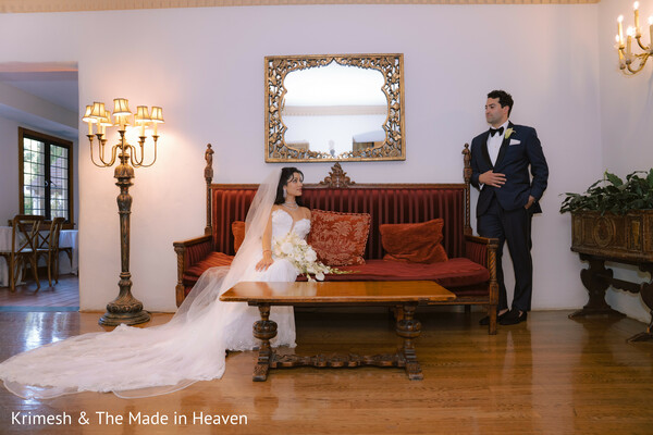 bride groom editorial portrait,indoor wedding photoshoot,vintage sofa setting,bride veil long train,groom tuxedo pose,elegant wedding styling,classic interior decor,romantic composition,posed couple portrait,luxury wedding vibe