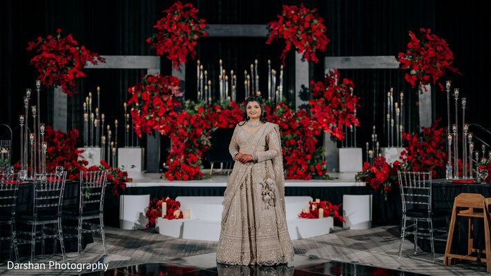 indian bride portrait,reception look,red floral backdrop,luxury wedding decor,bridal fashion,elegant bride,wedding stage,editorial portrait,dramatic lighting,reception styling