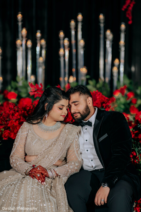 romantic couple portrait,close up couple,wedding reception,indian bride and groom,candlelight portrait,emotional moment,luxury wedding,red floral backdrop,intimate wedding moment,elegant couple