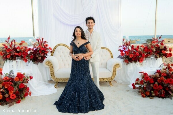reception portraits,sweetheart table,red floral decor,beachfront wedding,evening elegance,formal attire,destination reception,luxury wedding design,newlywed portraits,romantic setting