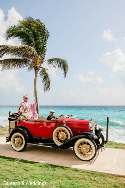 groom entrance,vintage convertible,baraat arrival,beach wedding,destination wedding,luxury transportation,oceanfront venue,groom fashion,tropical celebration,wedding traditions