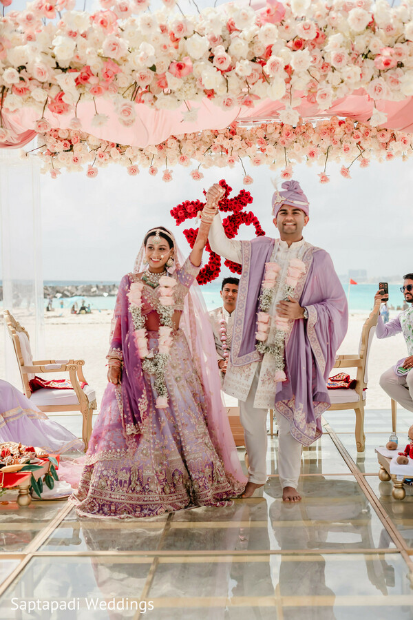 newlywed celebration,wedding ceremony,bride and groom,floral canopy,destination wedding,hindu wedding,wedding exit,joyful moments,luxury decor,oceanfront venue