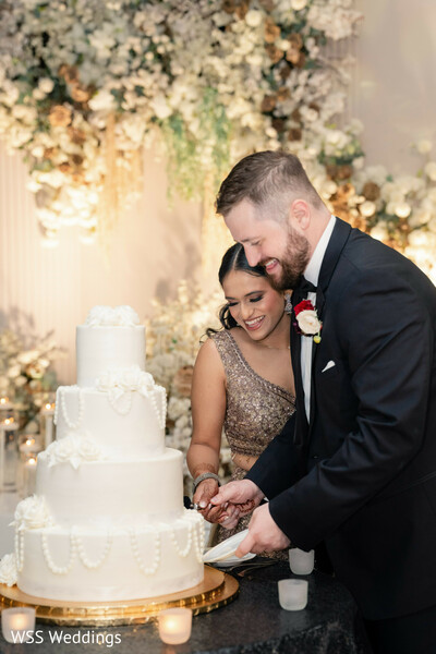cake cutting,wedding reception,newlyweds,luxury wedding cake,reception traditions,evening celebration,bride and groom,formal attire,romantic moments,wedding details