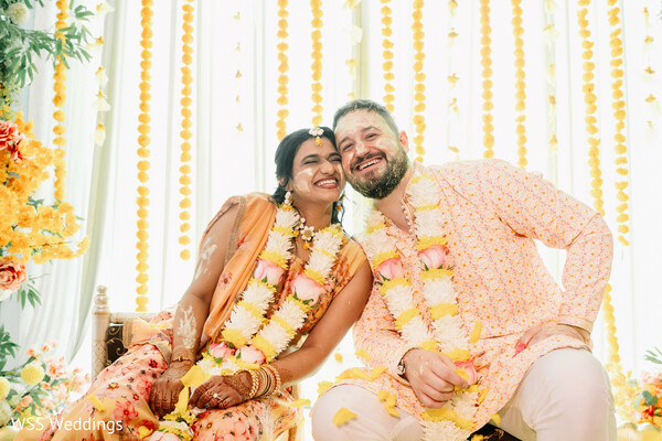 haldi ceremony,turmeric ritual,floral garlands,candid smiles,pre wedding rituals,bride and groom,cultural traditions,wedding festivities,joyful moments,south asian wedding