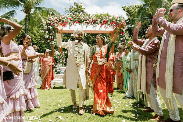 wedding exit,floral arch,newlyweds,flower petals,wedding ceremony,joyful celebration,destination wedding,bride and groom,outdoor ceremony,wedding traditions