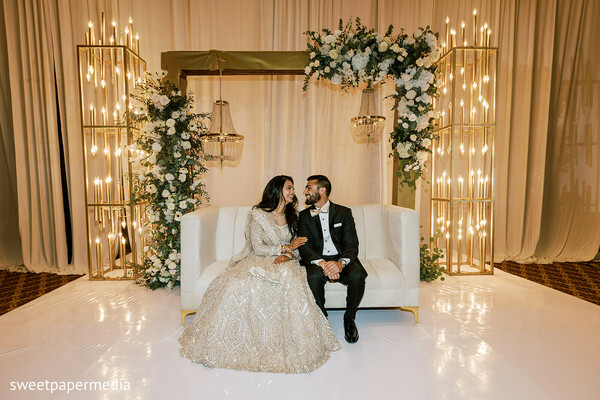 reception stage,luxury decor,floral backdrop,formal attire,bride and groom,wedding reception,elegant portraits,evening celebration,glamorous wedding,romantic moments