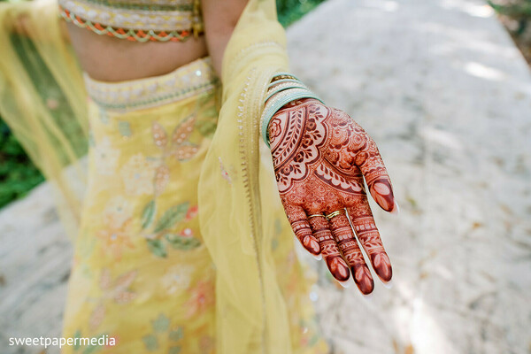 bridal mehndi,henna details,yellow lehenga,floral outfit,bridal bangles,intricate patterns,pre wedding ceremony,mehndi closeup,south asian bride,wedding traditions