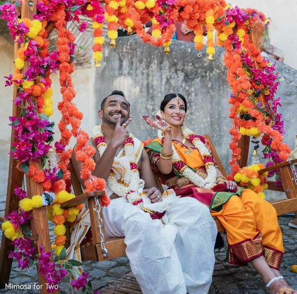 couple portraits,floral swing,wedding decor,colorful florals,candid moments,cultural celebration,pre wedding events,wedding photography,festive atmosphere,joyful portraits