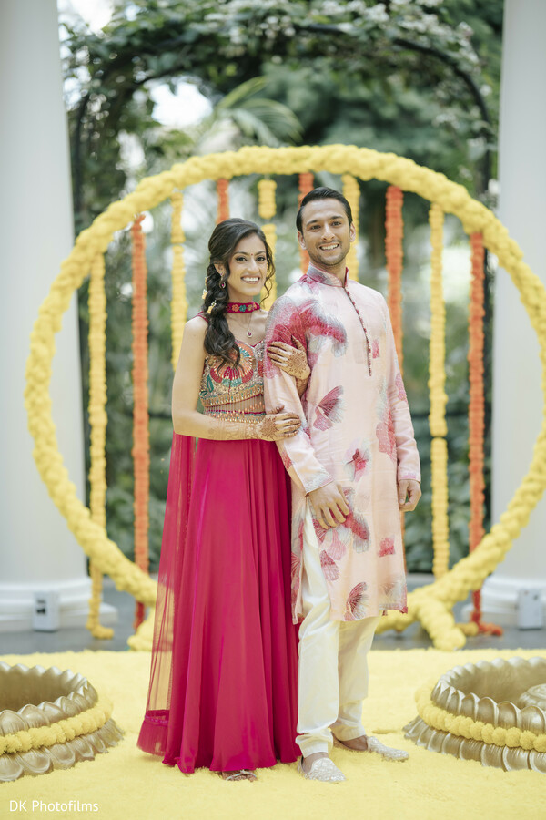 haldi,pre wedding celebration,couple portraits,colorful decor,floral backdrop,wedding traditions,outdoor event,vibrant wedding,south asian wedding,festive decor