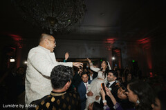 Joyful Indian Bride Lifted by Guests at Grand Ballroom Reception