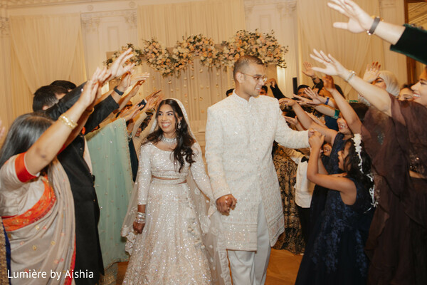 indian wedding,reception entrance,grand entrance,white lehenga,white sherwani,floral arch,wedding celebration,south asian couple,bridal entrance,groom entrance