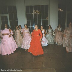 Woman in Red Outfit Leads Dance Performance with Others in Pink and Silver