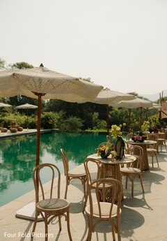 Outdoor Poolside Event Setup with Woven Umbrellas and Floral Decor