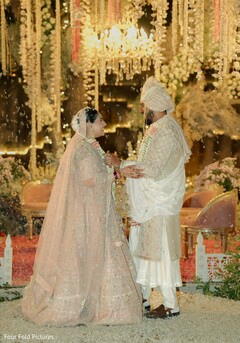 Couple in traditional attire under floral and chandelier decor