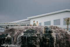 Couple on Rocky Cliffside with Modern Building