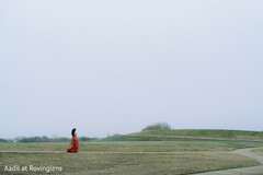 Indian Bride in Red Lengha Walking on Grassy Hillside