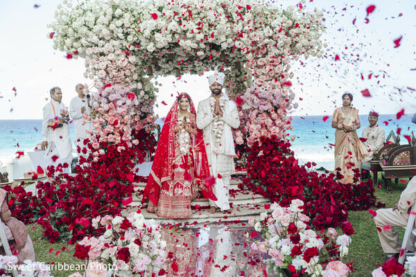 floral arch,rose petals,red outfit,white outfit,outdoor ceremony,wedding attire,floral decor,ocean view,south asian wedding,wedding fashion
