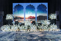 Elegant Stage Decor with Floral Arrangements and Scenic Backdrop