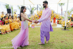 Couple in pink and purple outfits with floral decor at outdoor event