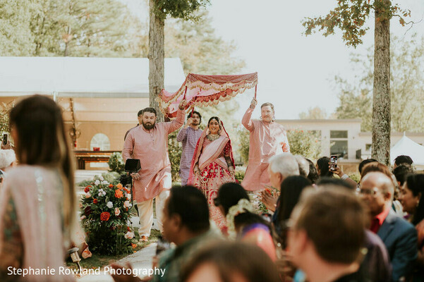 bridal entrance,outdoor ceremony,red lehenga,white lehenga,wedding canopy,wedding guests,floral decor,wedding fashion,ceremony decor,outdoor wedding