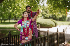 Couple in traditional attire on a walkway with floral garlands