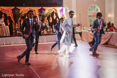 Groom and wedding party dance in suits and kurta at reception