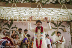 Groom in traditional attire under floral decor