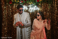 Couple dancing with sunglasses in front of a sequin backdrop