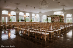 Elegant Indoor Ceremony Setup with Floral Mandap and Gold Chairs
