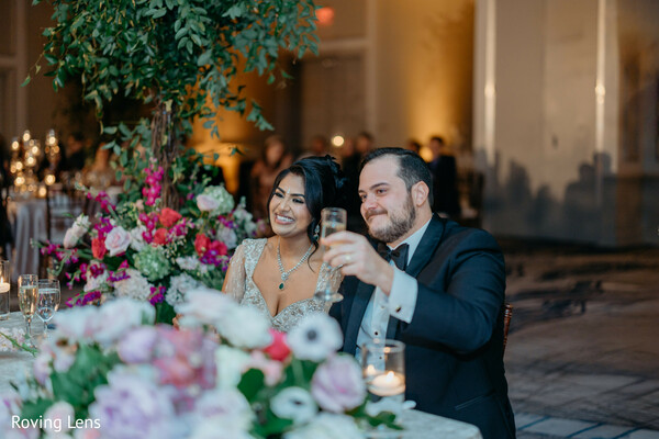 wedding reception,champagne toast,bride and groom,reception decor,floral centerpieces,candid smiles,evening celebration,elegant reception,newlyweds,south asian wedding