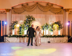 Couple Poses in Front of Stage with Floral Arches