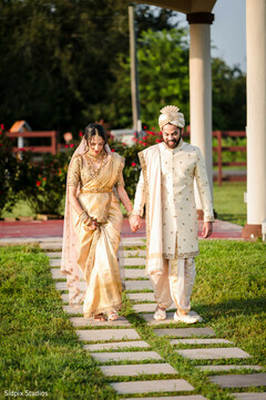 Couple in Golden Attire Walks on Stone Path