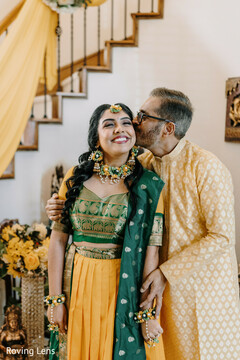 Bride in yellow lehenga and green blouse receives a kiss