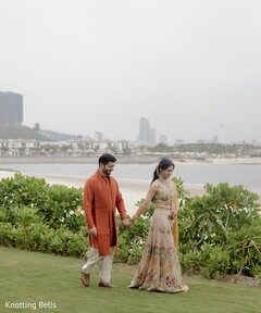Couple in Floral Lehenga and Orange Kurta on a Grassy Hillside