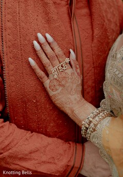 Bride's Hand Adorned with Intricate Mehndi, Stacked Bracelets, and a Unique Ring