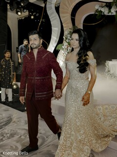 Couple in Sparkling Gown and Maroon Jacket Walk Hand-in-Hand