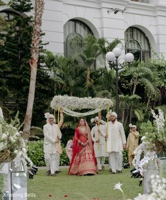 Bride in Red Lehenga Enters Under Floral Canopy