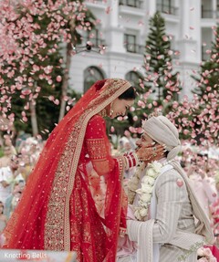 Rose Petal Shower Enhances Red Bridal Lehenga & Neutral Groom Attire