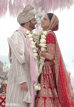 Couple in Red and Gold Lehenga and Striped Sherwani with Floral Garlands
