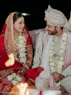 Bride and Groom in Red Lehenga and Cream Sherwani with White Rose Malas by Fire