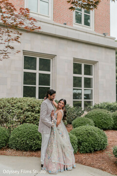 Couple Poses by Modern Building with Green Landscaping