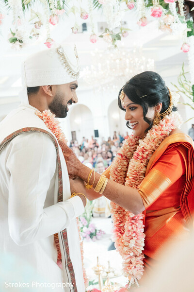 wedding ceremony,bride,groom,floral garlands,red sari,white kurta,wedding attire,couple,wedding